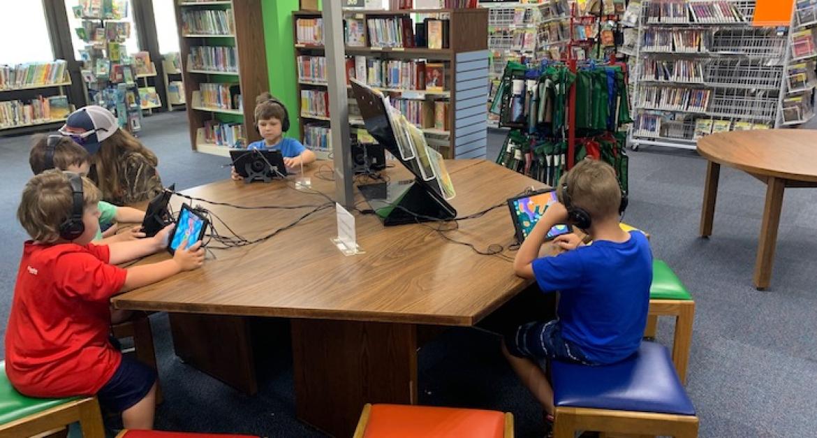 Children playing on tablets in library